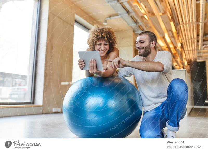 Happy man and woman using tablet on fitness ball in modern office Germany mindfulness aware awareness self-care Fitness Ball Fitness Balls Balance Ball