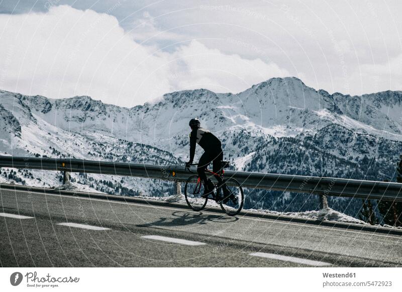 Andorra, cyclist on mountain road with snowy mountains in the background Mountain Road Mountain Roads snow-covered snow covered covered in snow people persons