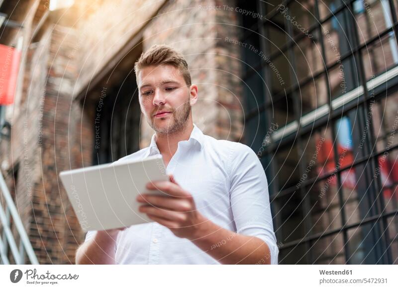 Young businessman using tablet at a brick building Occupation Work job jobs profession professional occupation business life business world business person