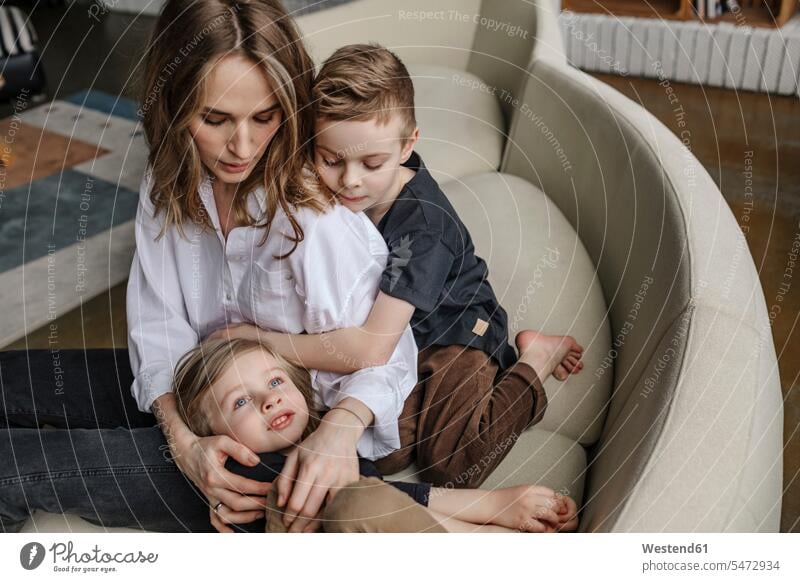 Blond woman sitting with sons on sofa in living room at home color image colour image indoors indoor shot indoor shots interior interior view Interiors