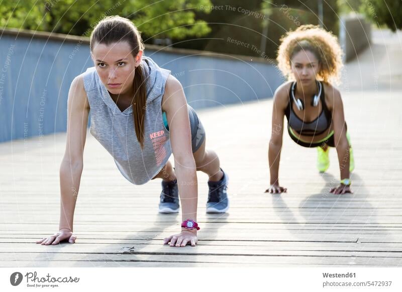 Two sporty young women doing push-ups on a bridge human human being human beings humans person persons caucasian appearance caucasian ethnicity european 2