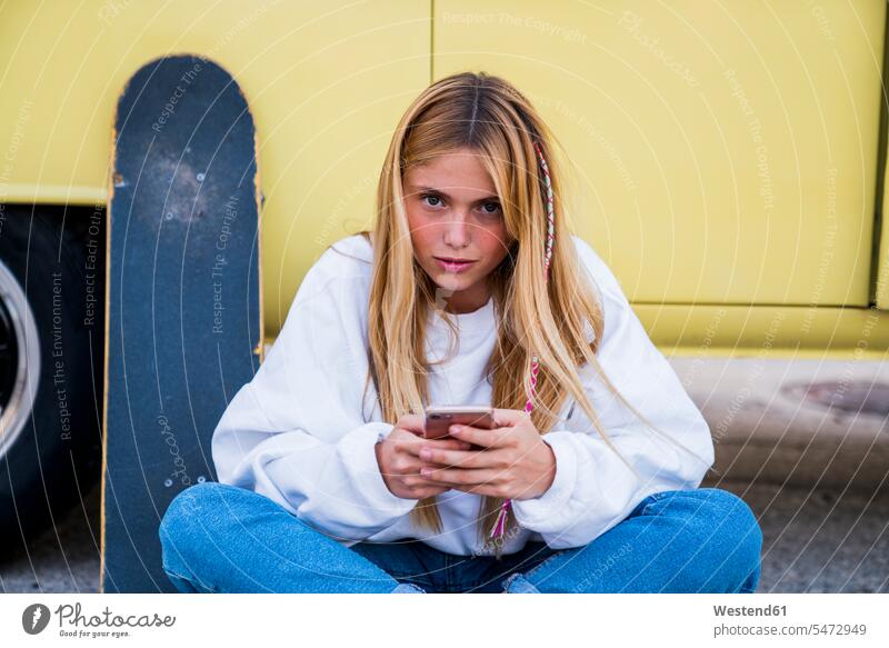 Young woman with skateboard and cell phone sitting at a van portrait portraits Skate Board skateboards mobile phone mobiles mobile phones Cellphone cell phones
