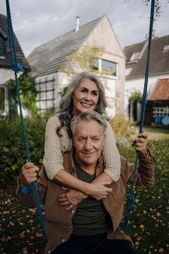 Happy woman embracing senior man on a swing in garden human human being human beings humans person persons caucasian appearance caucasian ethnicity european 2