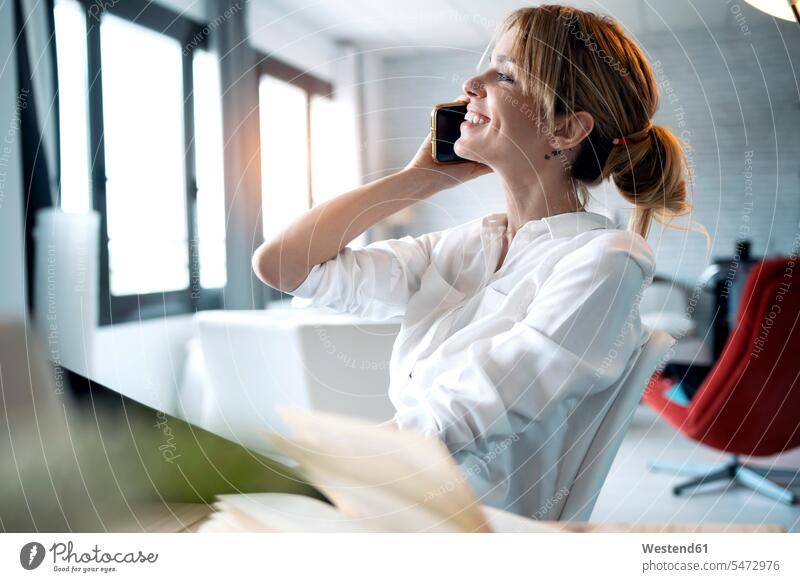 Smiling woman talking on phone at home office color image colour image indoors indoor shot indoor shots interior interior view Interiors businesswoman