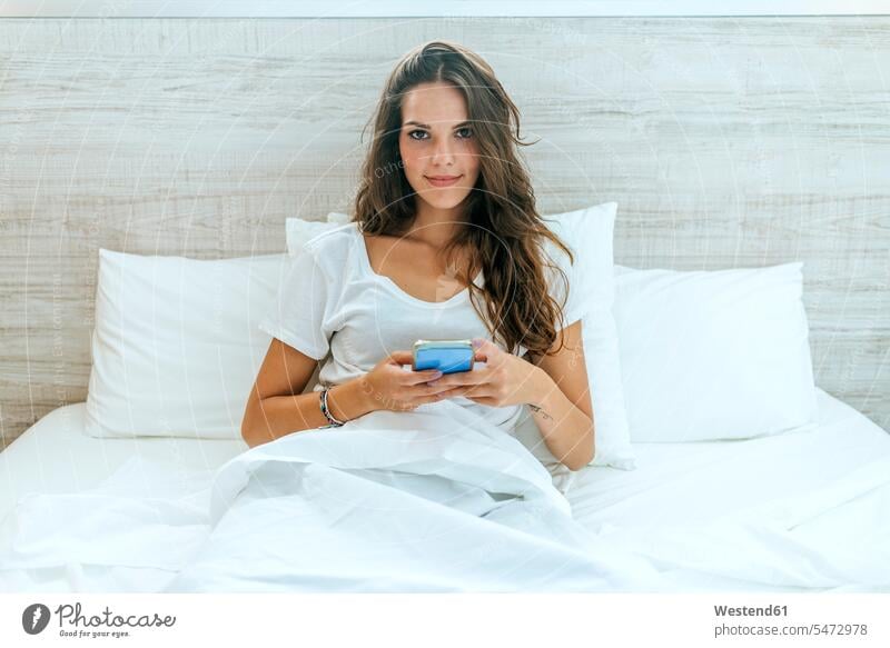 Portrait of young woman with cell phone in bed at home human human being human beings humans person persons caucasian appearance caucasian ethnicity european 1