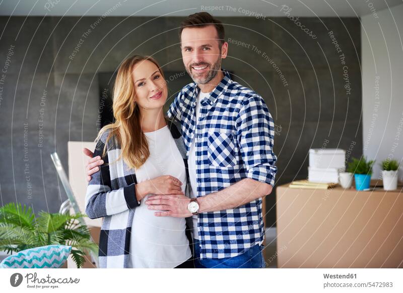 Portrait of happy man and pregnant woman moving into new flat portrait portraits flats apartment apartments move in couple twosomes partnership couples
