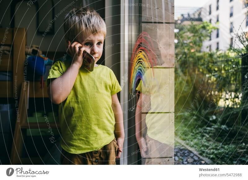 Portrait of little boy on the phone at home windows pane panes window glass window glasses Window Pane windowpanes T- Shirt t-shirts tee-shirt telecommunication