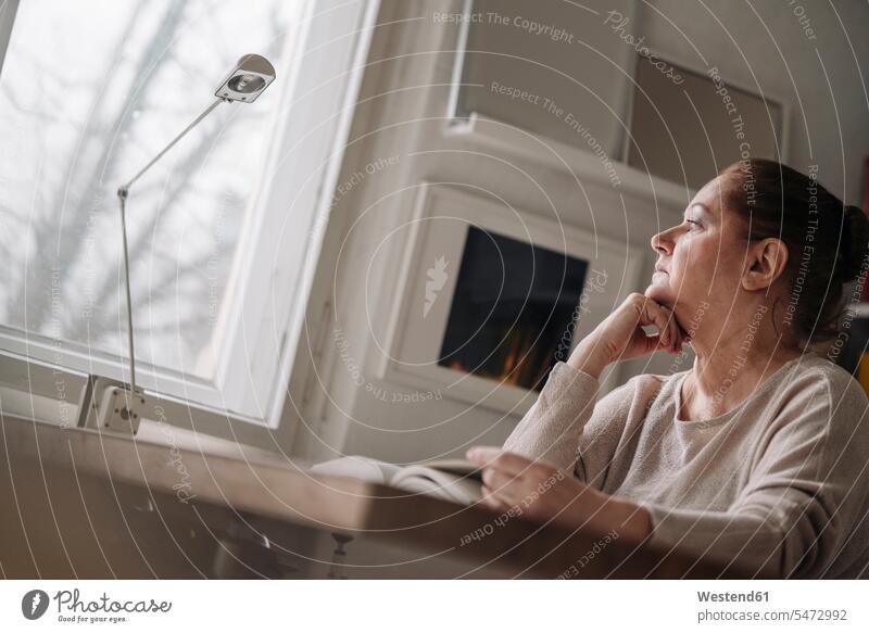 Senior woman with book at home looking out of window human human being human beings humans person persons caucasian appearance caucasian ethnicity european 1