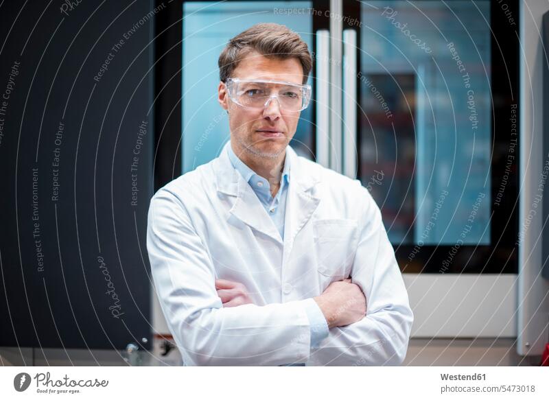 Portrait of man wearing lab coat and safety goggles at machine men males portrait portraits Laboratory Coat Labcoats Lab Coat Laboratory Coats Lab Coats