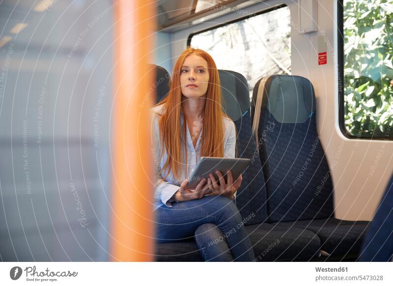 Thoughtful young woman holding digital tablet while sitting in train color image colour image Train Interior railway railroad Railways railroads transportation