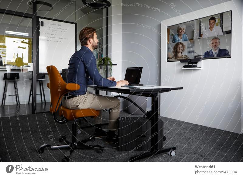 Businessman attending web conference while sitting in office color image colour image indoors indoor shot indoor shots interior interior view Interiors day