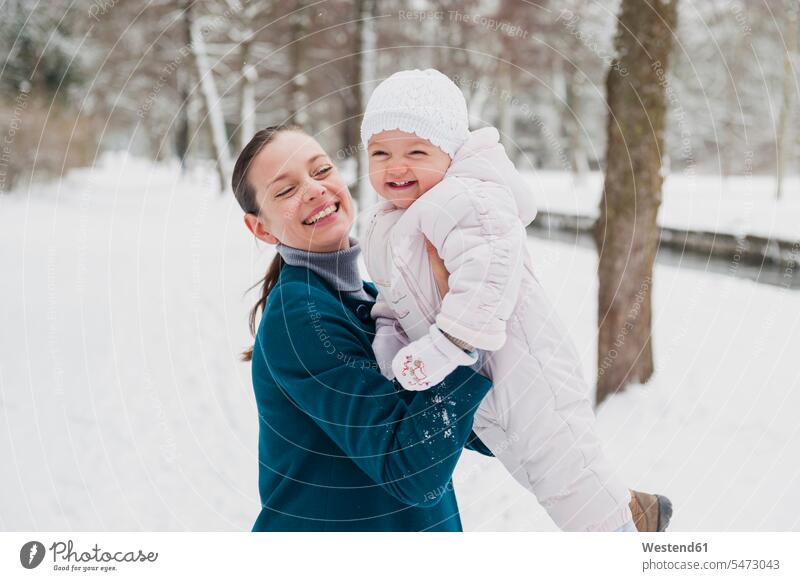 Portrait of happy baby girl having fun with her mother in snow-covered landscape happiness baby girls female mommy mothers mummy mama snow covered
