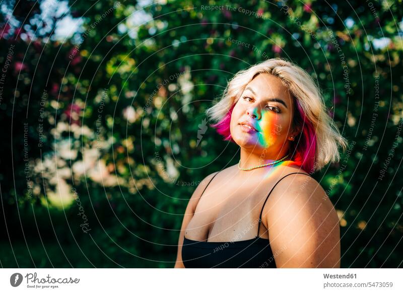 Plus size woman with rainbow lights falling on her face in park color image colour image outdoors location shots outdoor shot outdoor shots day daylight shot