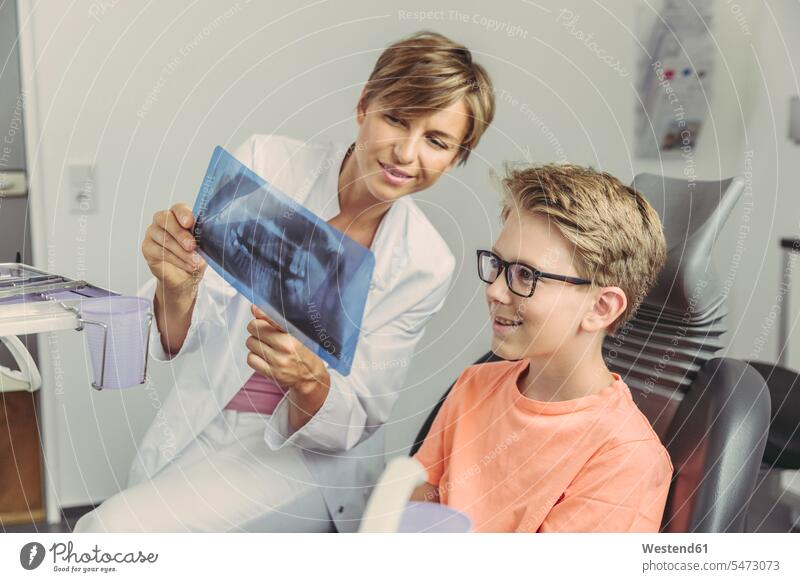 Female dentist explaining boy a x-ray image boys males x-rays radiography radiographies Showing show smiling smile female dentist female dentists