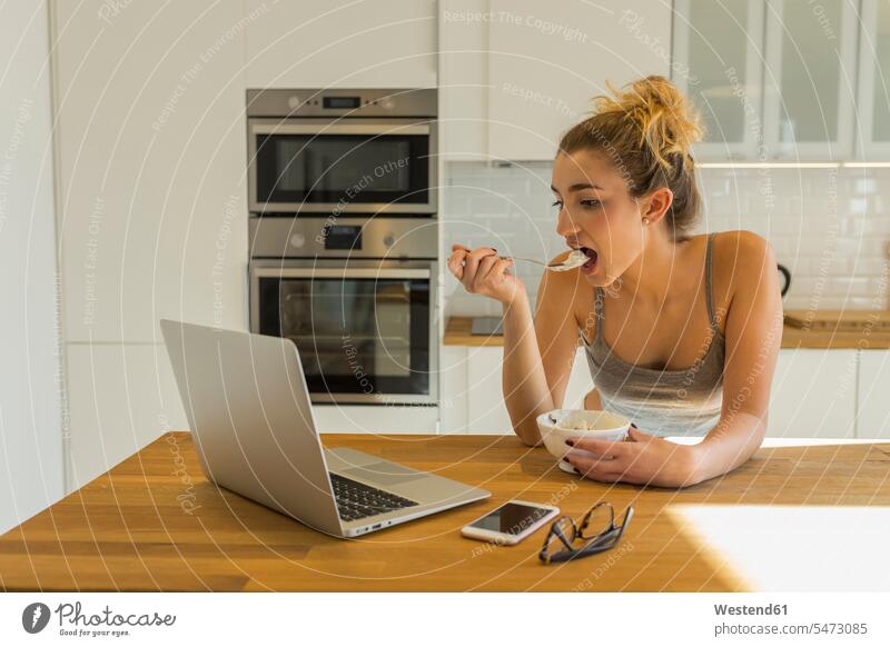 Female teenager using laptop during breakfast in the kitchen Bowls computers Laptop Computer Laptop Computers laptops notebook telecommunication phones