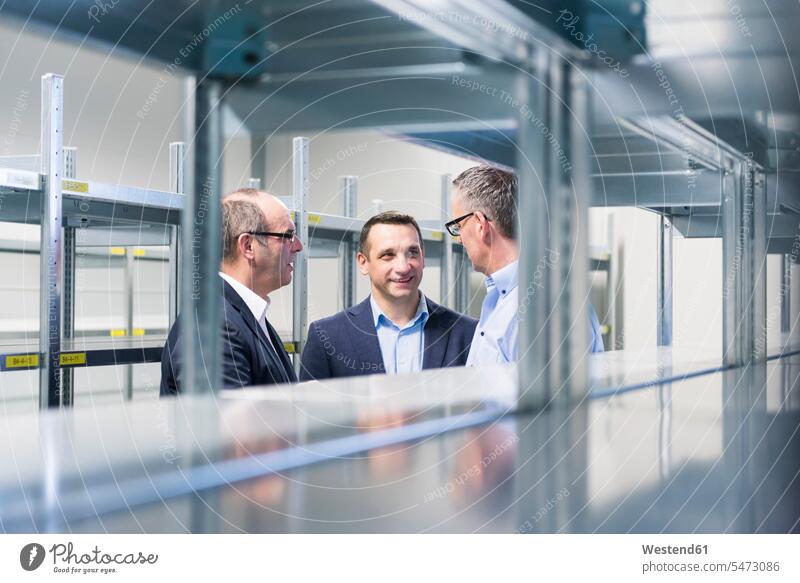 Three businessmen having a discussion in a factory storehouse human human being human beings humans person persons caucasian appearance caucasian ethnicity