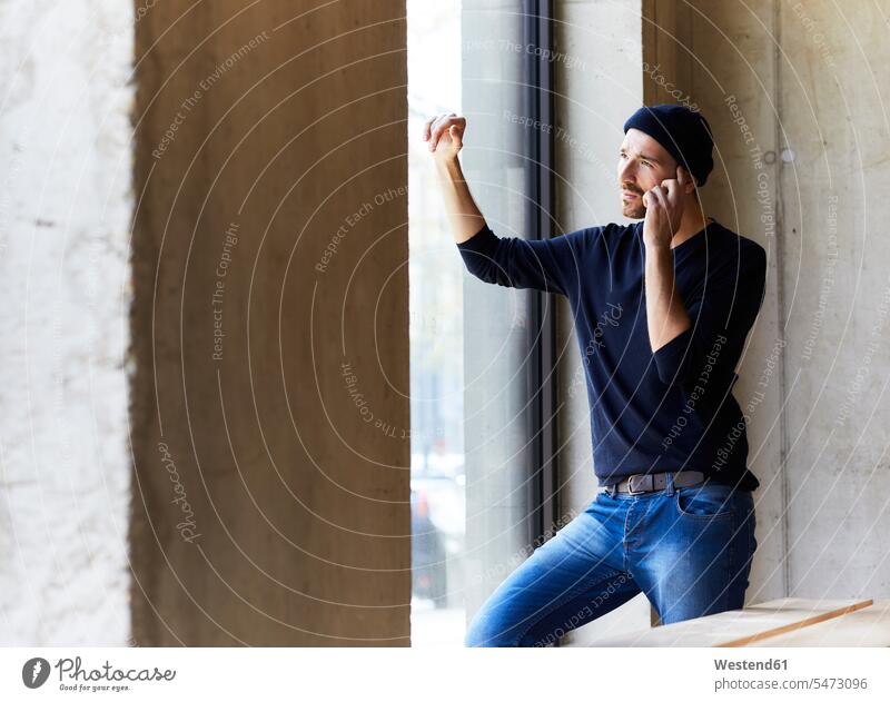 Young man on the phone looking out of window Germany thinking concrete listening wireless Wireless Connection Wireless Technology Wireless Communication