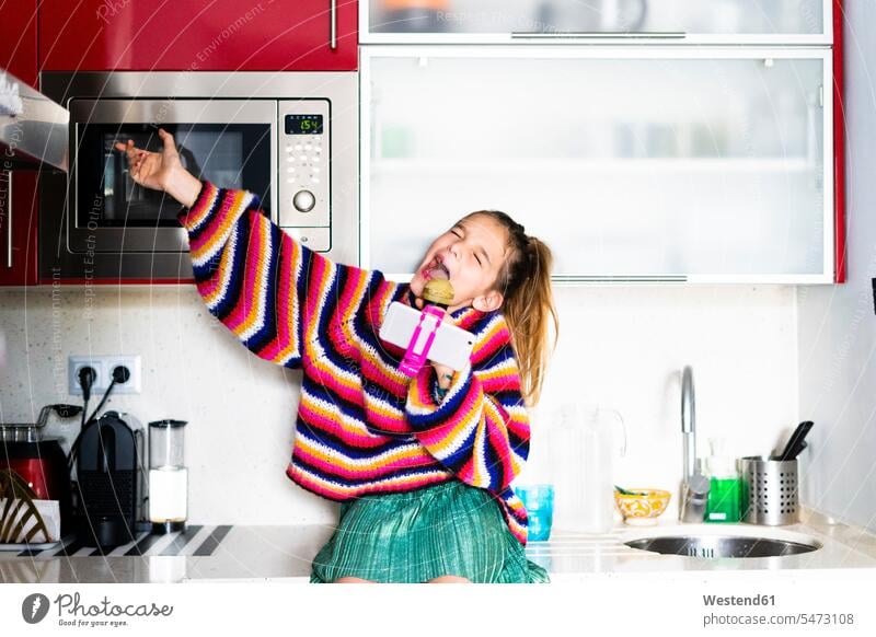 Girl playing with microphone and smartphone in kitchen at home Smartphone iPhone Smartphones girl females girls microphones micros mobile phone mobiles
