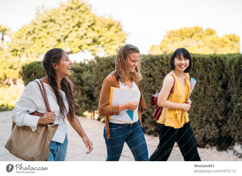 Three happy female friends walking around in a park human human being human beings humans person persons caucasian appearance caucasian ethnicity european Asian