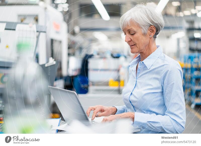 Senior businesswoman using laptop in a factory Laptop Computers laptops notebook factories businesswomen business woman business women computer computers