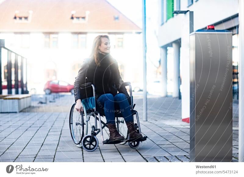 Young woman in wheelchair in the city wheelchairs town cities towns females women outdoors outdoor shots location shot location shots Adults grown-ups grownups