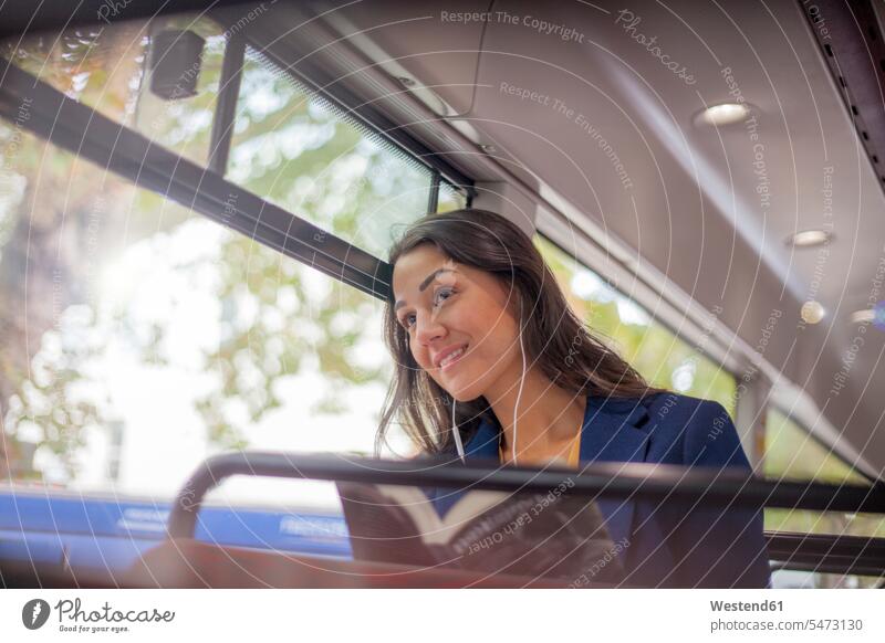 Young woman listening music on a bus with earphones, looking out of window business life business world business person businesspeople business woman