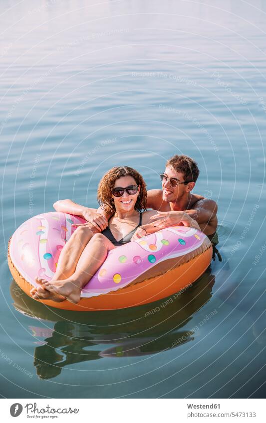 Happy young couple bathing in the sea on inflatable float in donut shape touristic tourists swim wear bikinis air bed air beds air mattress air mattresses