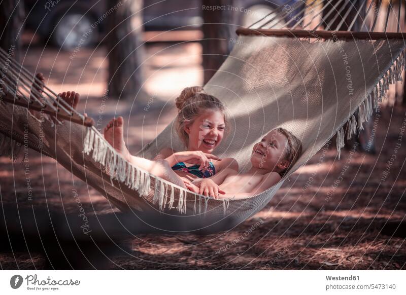 Happy girls relaxing on hammock at beach during summer color image colour image outdoors location shots outdoor shot outdoor shots day daylight shot