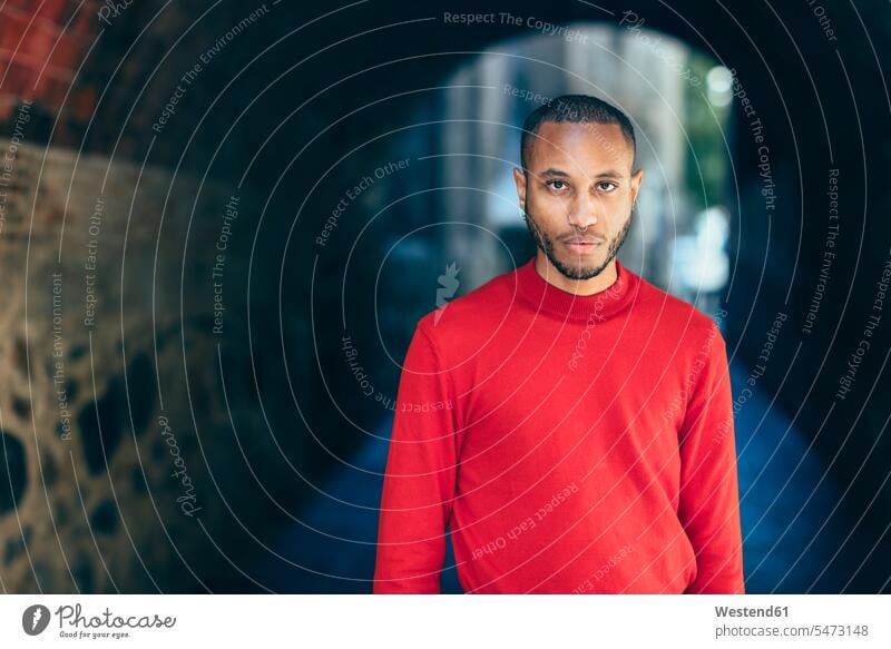 Portrait of young man in an underpass wearing red pullover sweater jumper Sweaters underpasses men males portrait portraits colour colours Adults grown-ups