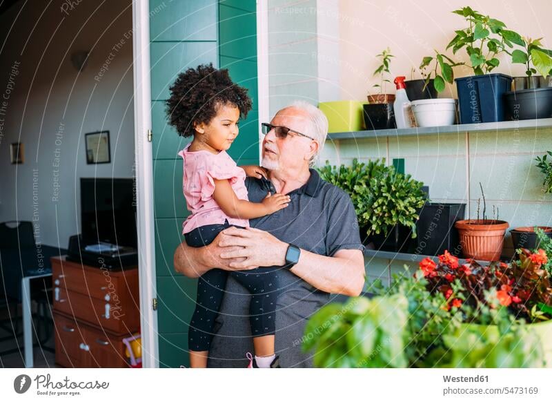 Grandfather wearing sunglasses carrying granddaughter in balcony color image colour image leisure activity leisure activities free time leisure time