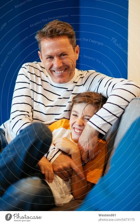 Happy father tickling son on couch at home settee sofa sofas couches settees happiness happy pa fathers daddy dads papa tickle sons manchild manchildren parents