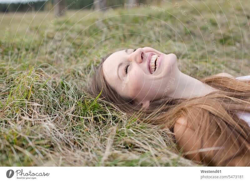 Laughing young woman lying on a meadow females women meadows laughing Laughter laying down lie lying down Adults grown-ups grownups adult people persons