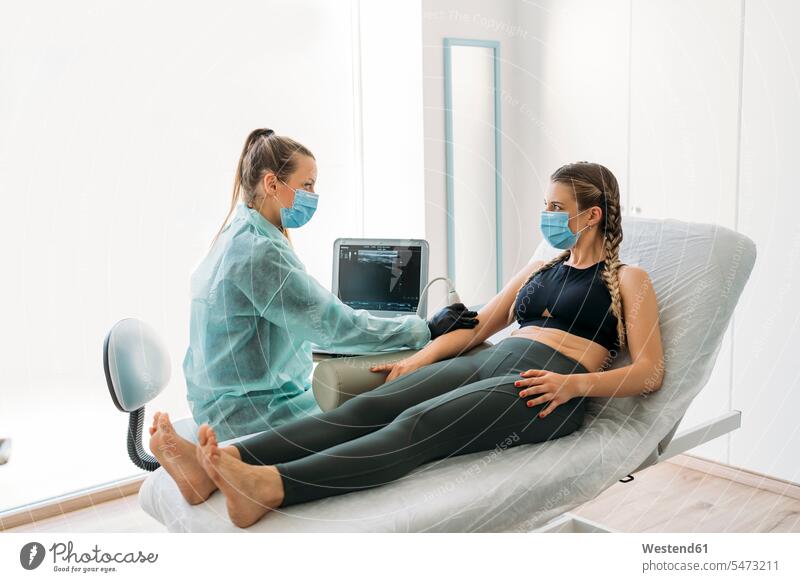 Doctor wearing face mask examining sportswoman with ultrasound scanner Occupation Work job jobs profession professional occupation lounges computers monitor