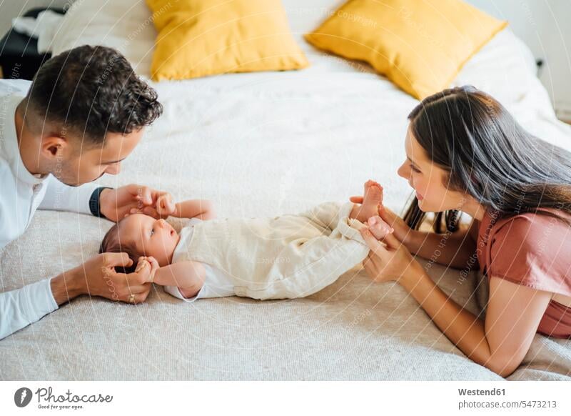 Happy parents holding baby boy on bed at home color image colour image indoors indoor shot indoor shots interior interior view Interiors day daylight shot