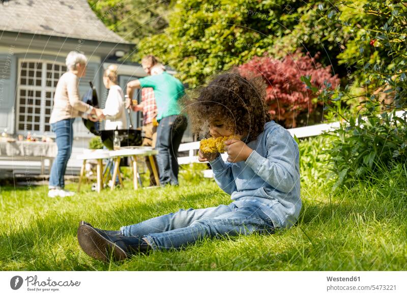 Boy eating a corn cob on a family barbecue in garden generation human human being human beings humans person persons families Multi Generations Families