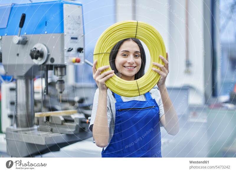 Happy female worker looking through rolled up cables in factory color image colour image indoors indoor shot indoor shots interior interior view Interiors day