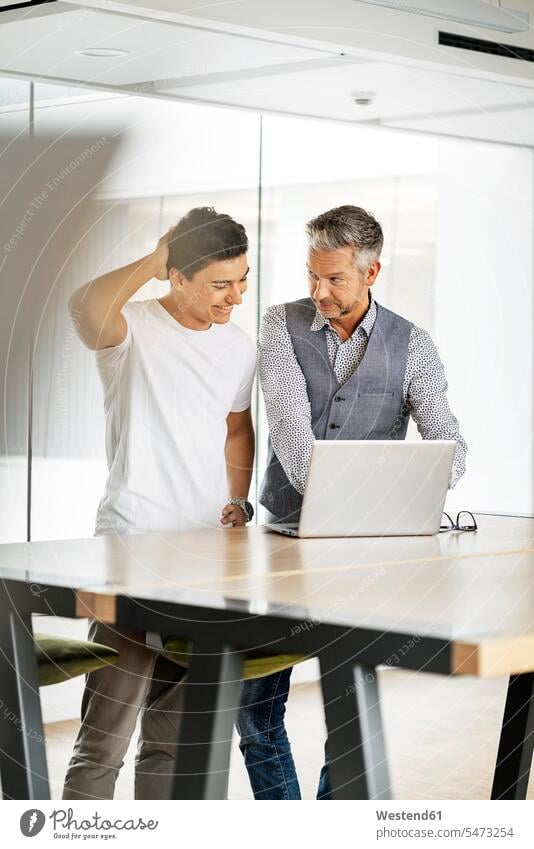 Senior businessman working with young colleague, using laptop human human being human beings humans person persons caucasian appearance caucasian ethnicity