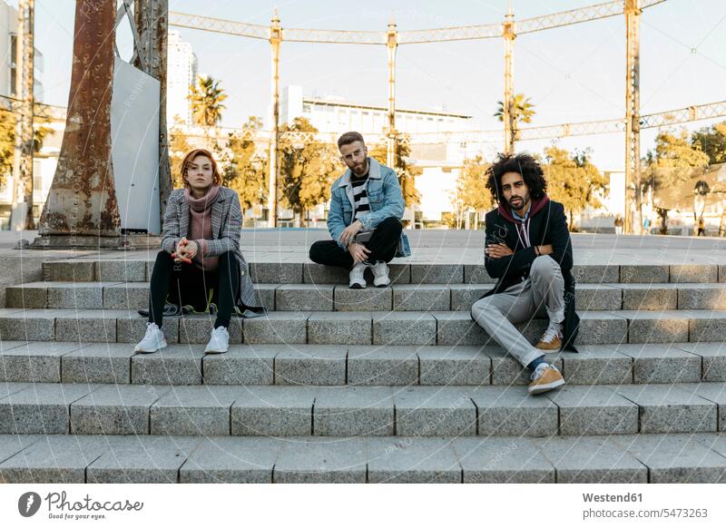 Portrait of three serious friends sitting on stairs stairway portrait portraits Seated earnest Seriousness austere friendship fashionable steps
