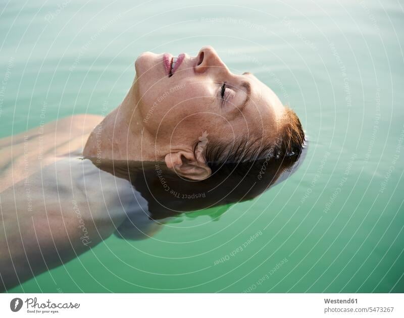 Mature woman floating in a lake with closed eyes human human being human beings humans person persons caucasian appearance caucasian ethnicity european 1