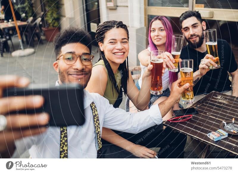 Happy friends holsing beer glasses and taking a selfie outdoors at a bar human human being human beings humans person persons caucasian appearance