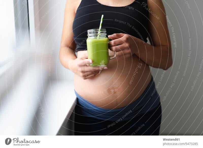 Young pregnant woman drinking fresh and healthy green smoothie Drinking Glass Drinking Glasses drinking straw drinking straws hold stand at home Pregnant Woman