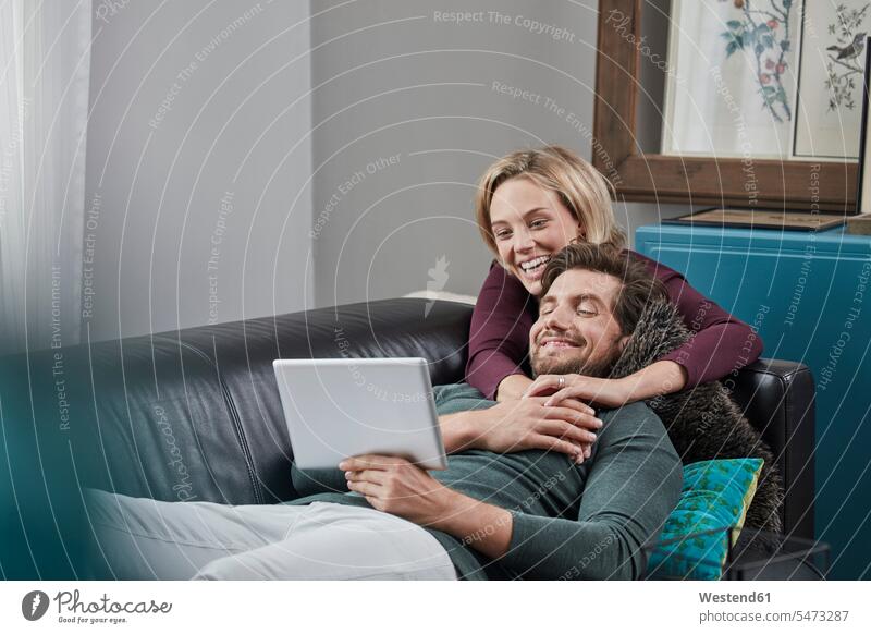 Happy couple with tablet on couch at home settee sofa sofas couches settees digitizer Tablet Computer Tablet PC Tablet Computers iPad Digital Tablet