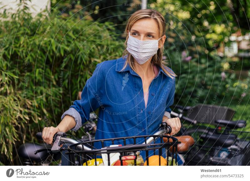 Woman wearing face mask with bicycle and shopped groceries in urban area dresses bikes bicycles bike - bicycle Cycle Cycle - Vehicle healthy protect protecting