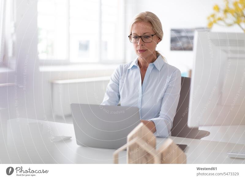 Businesswoman working over laptop on desk in home office color image colour image Germany indoors indoor shot indoor shots interior interior view Interiors