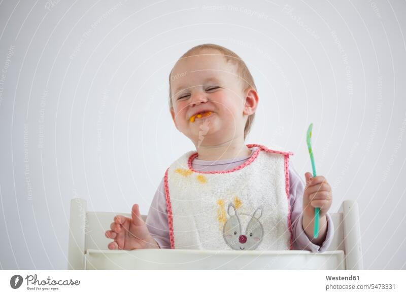 Portrait of smiling baby girl on high chair eating mush Pap High Chair baby high chair baby's high chair baby's high chairs High Chairs smile baby girls female