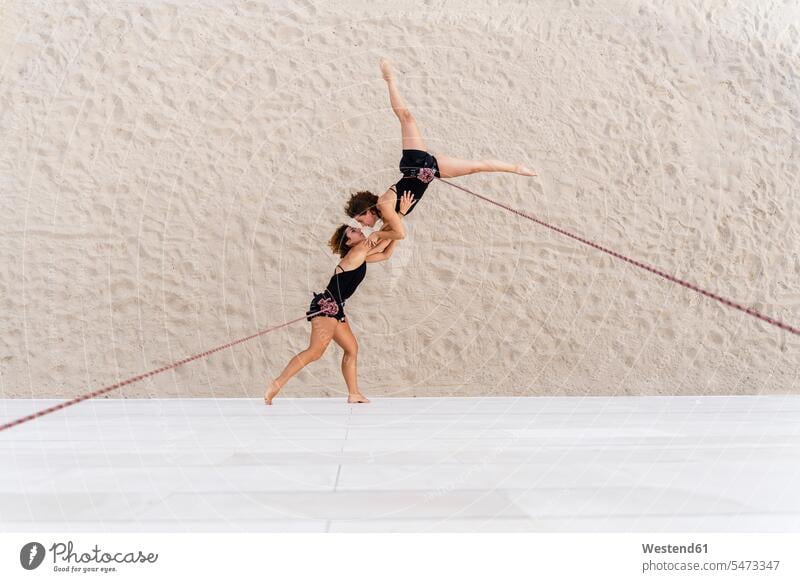 Aerial dancers dancing while hanging against wall color image colour image outdoors location shots outdoor shot outdoor shots day daylight shot daylight shots