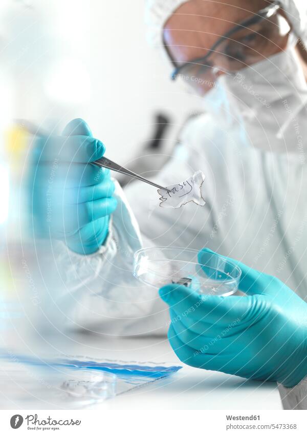 Forensic scientist examining fragments of paper in a laboratory (value=0) Occupation Work job jobs profession professional occupation At Work place of work