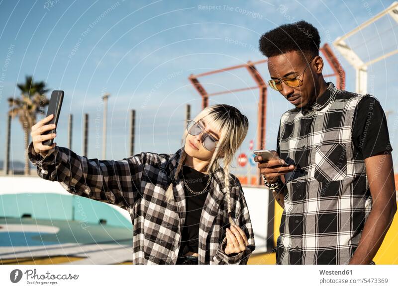 Young woman taking selfie with her boyfriend looking at his smartphone human human being human beings humans person persons caucasian appearance