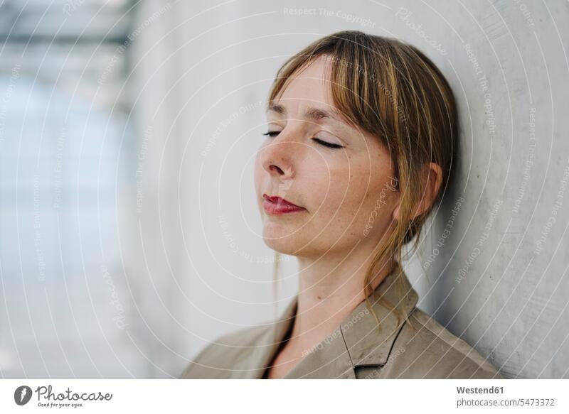 Portrait of a businesswoman with closed eyes leaning against a concrete wall Occupation Work job jobs profession professional occupation business life
