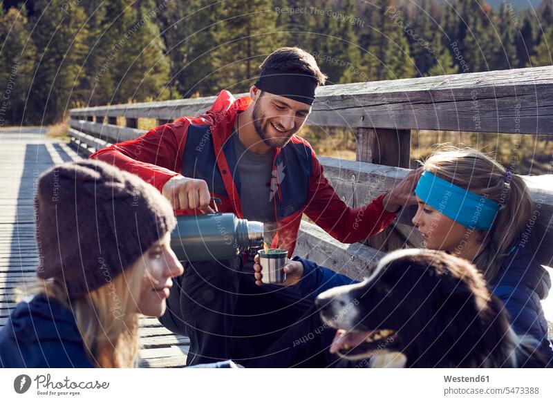 Group of friends with dog hiking resting on a bridge mate bridges hike dogs Canine friendship pets animal creatures animals break Recreational Pursuit